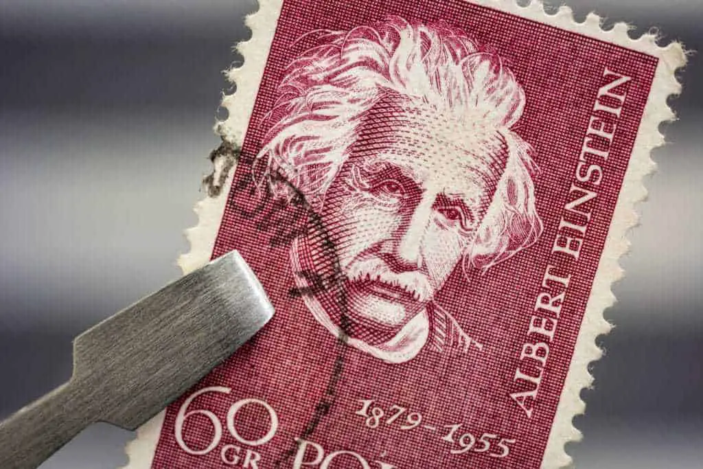 Albert Einstein Portrait On A Vintage Canceled Post Stamp From Poland Held By Tweezer Above A Page Of Stamp Album