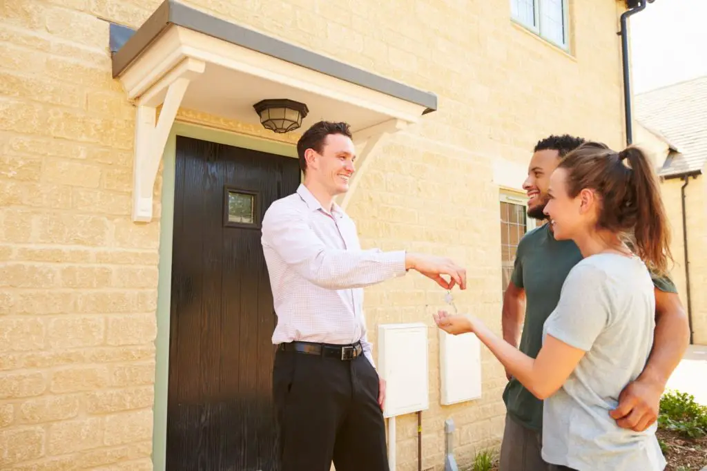 real estate agent giving key to home buyers