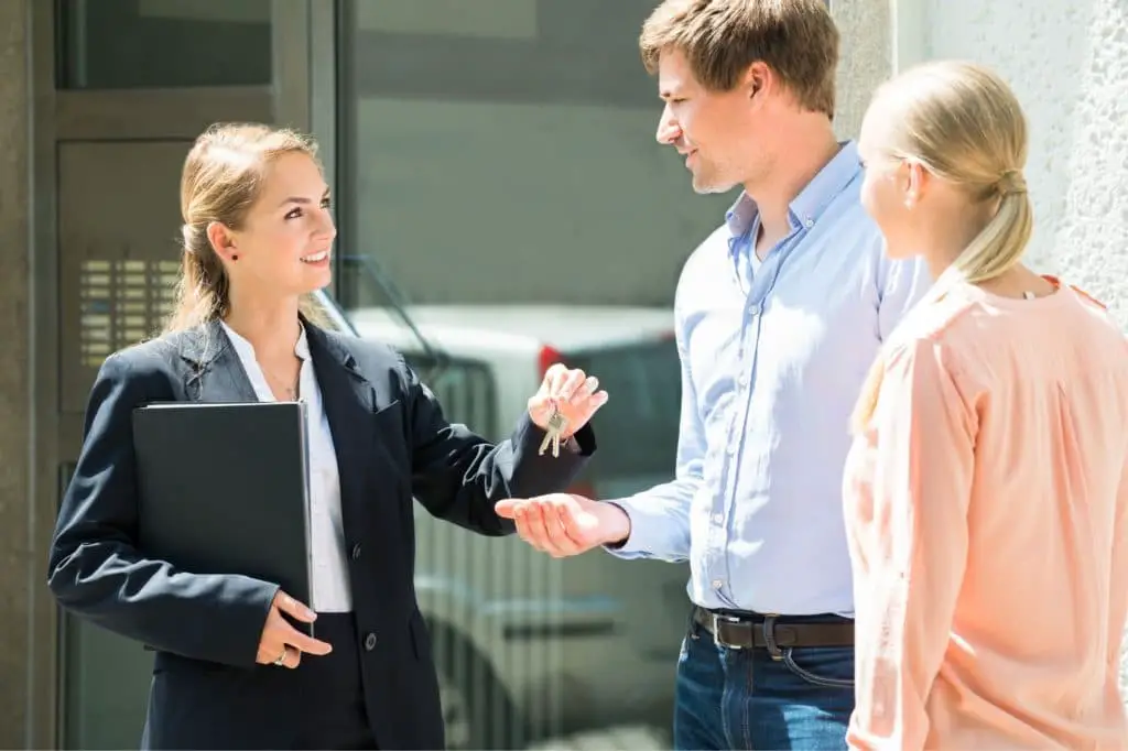 Real estate agent handling out keys to home owners